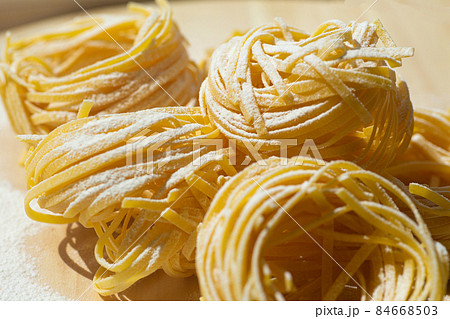 Fresh pasta food. Homemade Italian pasta cooked on a wooden background in a rustic style decorated with egg and flour. Fresh pasta food. Homemade Italian pasta cooked on a wooden background in a rustic style decorated with egg and flour. 84668503