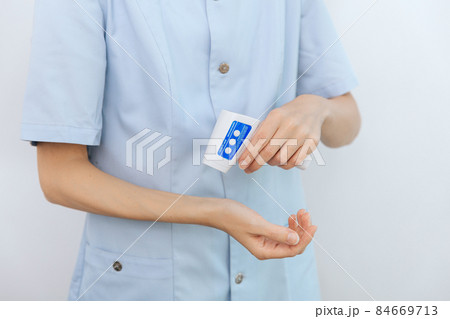 Temperature measurement gun in doctor hands. Close-up shot of doctor wearing protective surgical mask ready to use infrared isometric thermometer gun to check body temperature for virus symptoms. Temperature measurement gun in doctor hands. Close-up shot of doctor wearing protective surgical mask ready to use infrared isometric thermometer gun to check body temperature for virus symptoms. 84669713