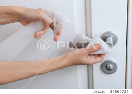 Cleaning white door handles with an antiseptic wet wipe and sanitizer spray. Disinfection in hospital and public spaces against corona virus. Woman hand using towel for cleaning home room door link. Cleaning white door handles with an antiseptic wet wipe and sanitizer spray. Disinfection in hospital and public spaces against corona virus. Woman hand using towel for cleaning home room door link. 84669722