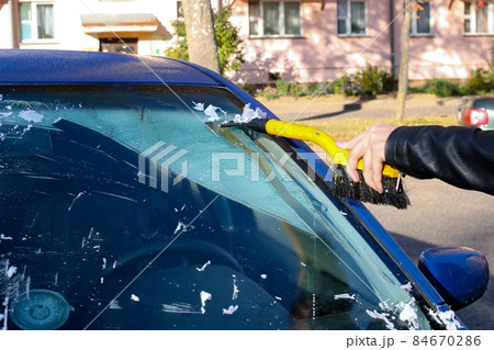 Hand cleans windshield of car from ice 84670286