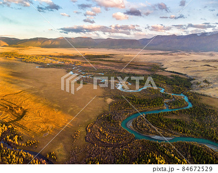 The Kurai steppe and the Chuya River against the background of the North Chuya ridge. Altai, Russia. Panoramic image from an aerial drone. 84672529