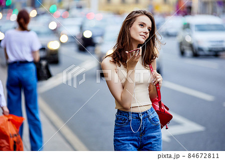 European woman 18 years old uses telephone in busy street. European woman 18 years old uses telephone in busy street. 84672811