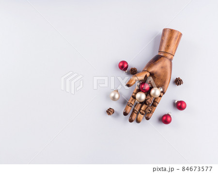Wooden hand with christmas red and golden ornaments on gray Wooden hand with christmas red and golden ornaments on gray 84673577
