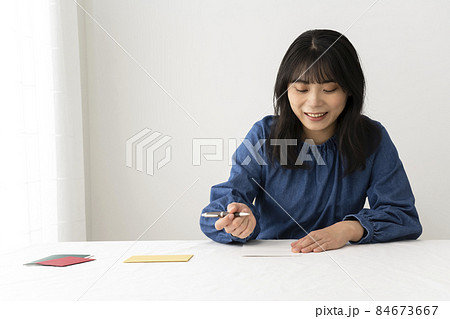 机でプレゼントと一緒に渡すメッセージカードを書く女性 机でプレゼントと一緒に渡すメッセージカードを書く女性 84673667