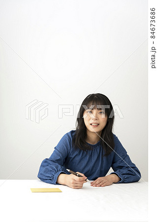 机でプレゼントと一緒に渡すメッセージカードを書く女性 机でプレゼントと一緒に渡すメッセージカードを書く女性 84673686