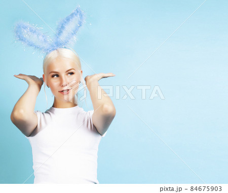 young pretty blond girl with rabbit ears posing cheerful on blue background, lifestyle people concept 84675903