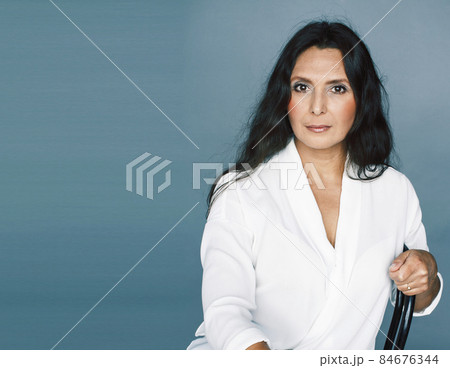 pretty brunette confident mature woman sitting on chair in studio, lifestyle people concept 84676344