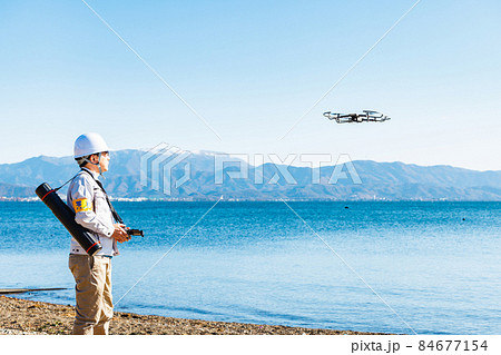 ドローンを操縦する作業員 84677154