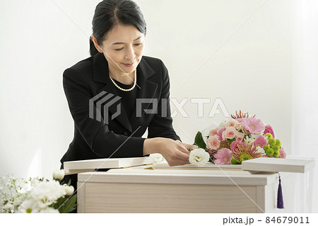 棺に花を入れる喪服姿の女性 84679011