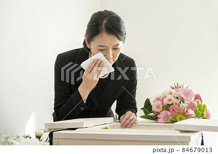 棺の前で涙を拭く喪服姿の女性 84679013
