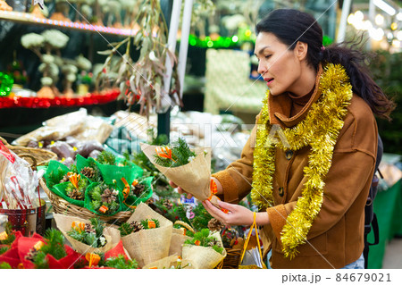 Woman choosing christmas decorations at fair Woman choosing christmas decorations at fair 84679021