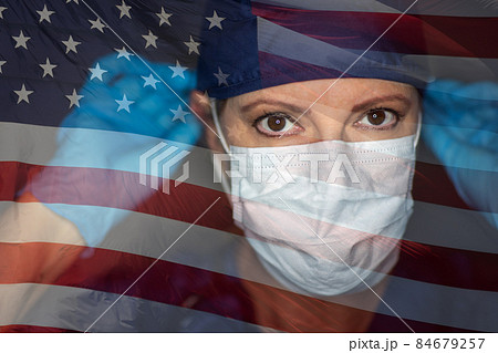 Doctor or Nurse Wearing Medical Face Mask and Scrubs with Ghosted American Flag. Doctor or Nurse Wearing Medical Face Mask and Scrubs with Ghosted American Flag. 84679257