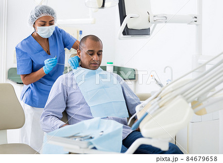 Dental assistant prepares patient for surgery Dental assistant prepares patient for surgery 84679658