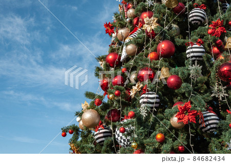 Christmas tree decorated with red baubles, bows and golden bells Christmas tree decorated with red baubles, bows and golden bells 84682434