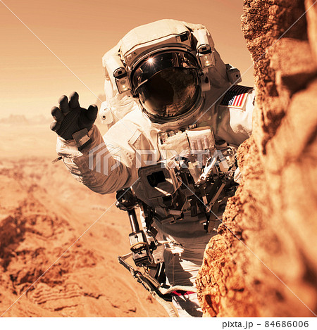 Astronaut Martian is on a mission to the red planet and climbs up a mountain on a rock. Space man conquers and populates the new planet Mars. Planet Mars and people, concept. Welcome to new home Astronaut Martian is on a mission to the red planet and climbs up a mountain on a rock. Space man conquers and populates the new planet Mars. Planet Mars and people, concept. Welcome to new home 84686006