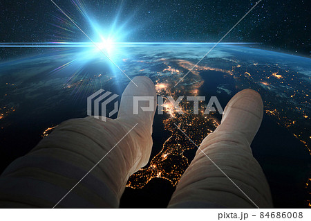 Spaceman sits and looks at the blue planet earth with night lights of cities from space. Astronaut feet on the background of the earth at blue sunset. Cosmos wallpaper. Man resting in orbit at sunrise Spaceman sits and looks at the blue planet earth with night lights of cities from space. Astronaut feet on the background of the earth at blue sunset. Cosmos wallpaper. Man resting in orbit at sunrise 84686008