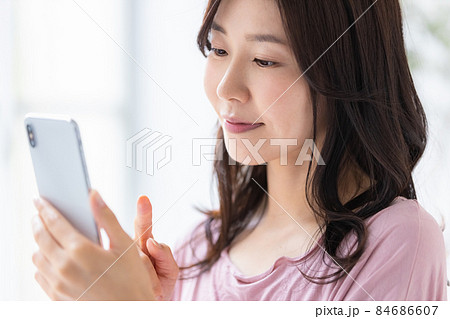 部屋着を着てスマホを操作する女性 84686607