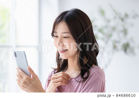 部屋着を着てスマホを操作する女性 84686610