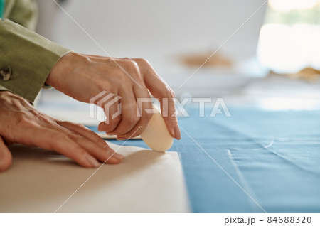 Dressmaker measures cloth on the table in workshop 84688320