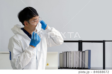 Asian scientist in virus protective cloth waring face mask before starting the experiment in a scientific laboratory. Asian scientist in virus protective cloth waring face mask before starting the experiment in a scientific laboratory. 84688672
