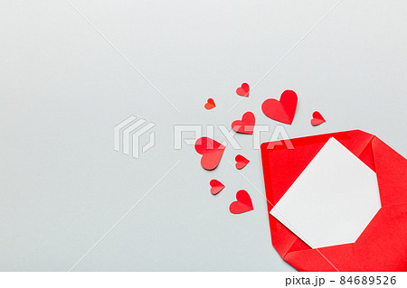 Red paper envelope with empty white card and heart on colored background. top view valentines day concept Red paper envelope with empty white card and heart on colored background. top view valentines day concept 84689526