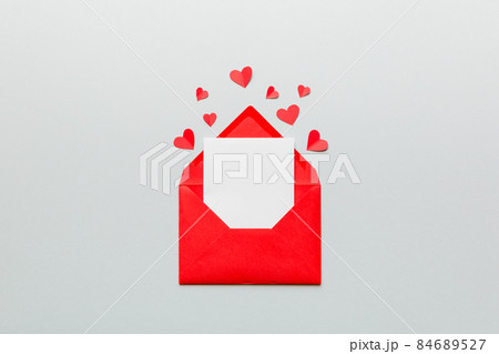 Red paper envelope with empty white card and heart on colored background. top view valentines day concept Red paper envelope with empty white card and heart on colored background. top view valentines day concept 84689527