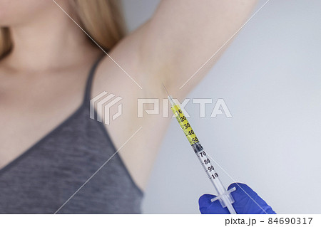 Woman receiving botulinum toxin injection in armpit as treatment of hyperhidrosis in clinic. Treatment of problems with increased sweating, anhidrosis, or malfunctioning glands. Cosmetology 84690317