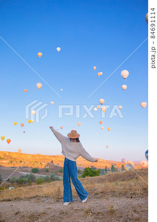 Happy woman during sunrise watching hot air balloons in Cappadocia, Turkey Happy woman during sunrise watching hot air balloons in Cappadocia, Turkey 84691114