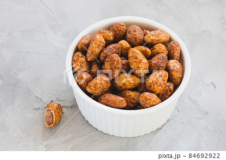 Candied or sugared almond with honey and cinnamon in a small porcelain plate on gray background. Traditional Christmas sweets for holidays. Copy space 84692922