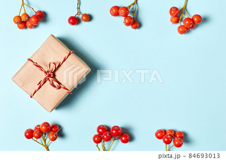 Christmas gift box on a blue background decorated with rowan berries with copy space 84693013