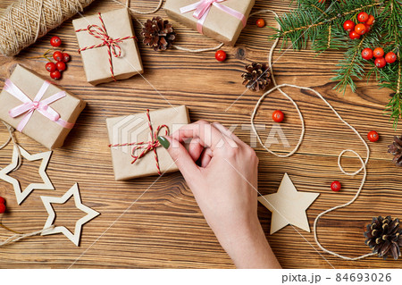 Girl unties the rope on the gift box on the background of christmas accessories Girl unties the rope on the gift box on the background of christmas accessories 84693026