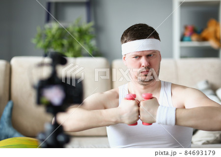 Strong middle aged man train on camera using pink dumbbells 84693179