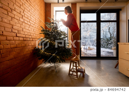 Woman decorating Christmas tree at home 84694742