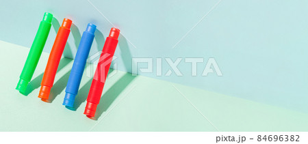 The straight folded pop tube stands leaning against the wall. Modern still life with antistress toy 84696382