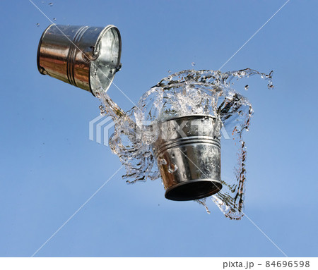 A pouring water from bucket to bucket, on a background of blue sky. 84696598