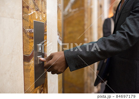 Hand of young African businessman pressing button to call elevator 84697179