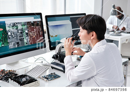 Young contemporary researcher with microscope 84697398