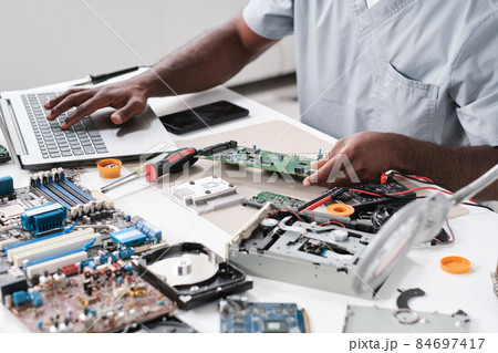 Hands of young blackman typing while holding part of hardware 84697417