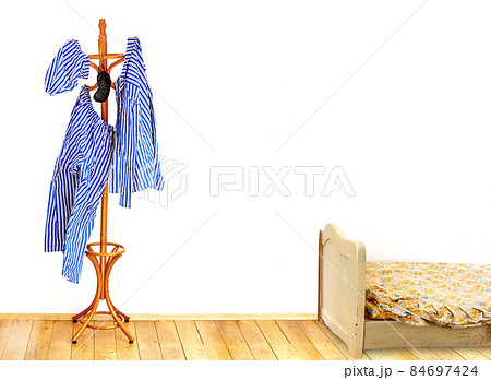 The striped pajamas hangs on the coat hook in an empty room with old bed. 84697424