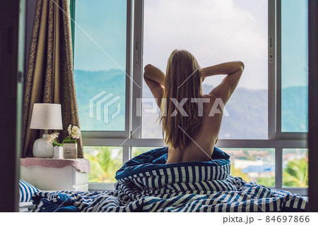 young happy woman woke up in the morning in the bedroom by the window with beautiful mountain views young happy woman woke up in the morning in the bedroom by the window with beautiful mountain views 84697866