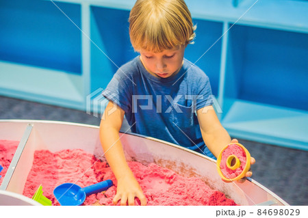 Boy playing with kinetic sand in preschool. The development of fine motor concept. Creativity Game concept Boy playing with kinetic sand in preschool. The development of fine motor concept. Creativity Game concept 84698029