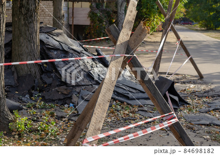 A pile of old roofing paper fenced with barrier tape. Work to re 84698182
