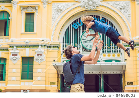 Father and son on background Saigon Central Post Office in Ho Chi Minh, Vietnam. On the building there is an inscription in Vietnamese: a post office 84698603