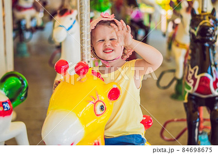 Cute little girl enjoying in funfair and riding on colorful carousel house 84698675