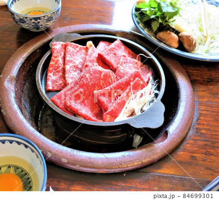 明治時代の昔ながらの牛鍋、すき焼き、和牛を黒い鉄鍋で焼いている様子、隣の大皿に野菜 明治時代の昔ながらの牛鍋、すき焼き、和牛を黒い鉄鍋で焼いている様子、隣の大皿に野菜 84699301