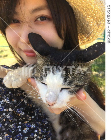 猫を抱っこする麦わら帽子をかぶった日本人女性　クローズアップ 84700121