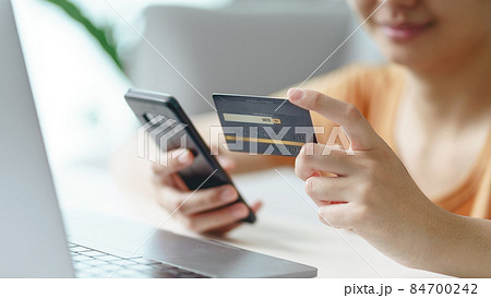 Young woman holding credit card and using smartphone for online shopping, internet banking, e-commerce, spending money, working from home concept 84700242