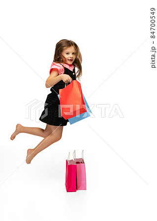 Portrait of beautiful little cute kid jumping with shopping packages isolated over white background. Portrait of beautiful little cute kid jumping with shopping packages isolated over white background. 84700549