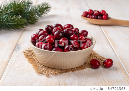 Ripe red cranberries in a beige bowl over white rustic wooden table. Ripe red cranberries in a beige bowl over white rustic wooden table. 84701363