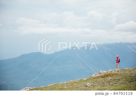 female traveler standing on top of a mountain looking at the view 84701519